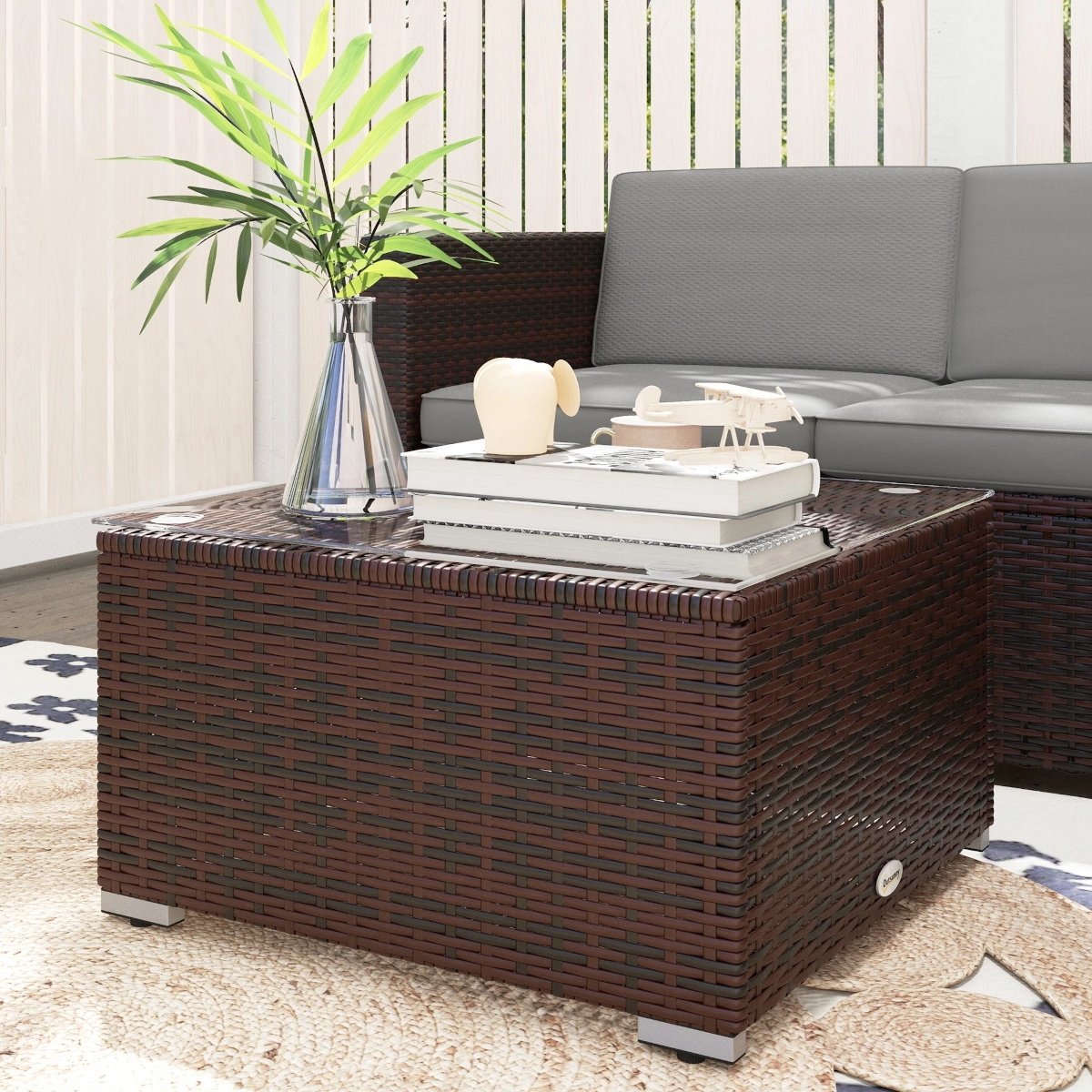 Cozy outdoor wicker furniture set with cushions and decorative plants.