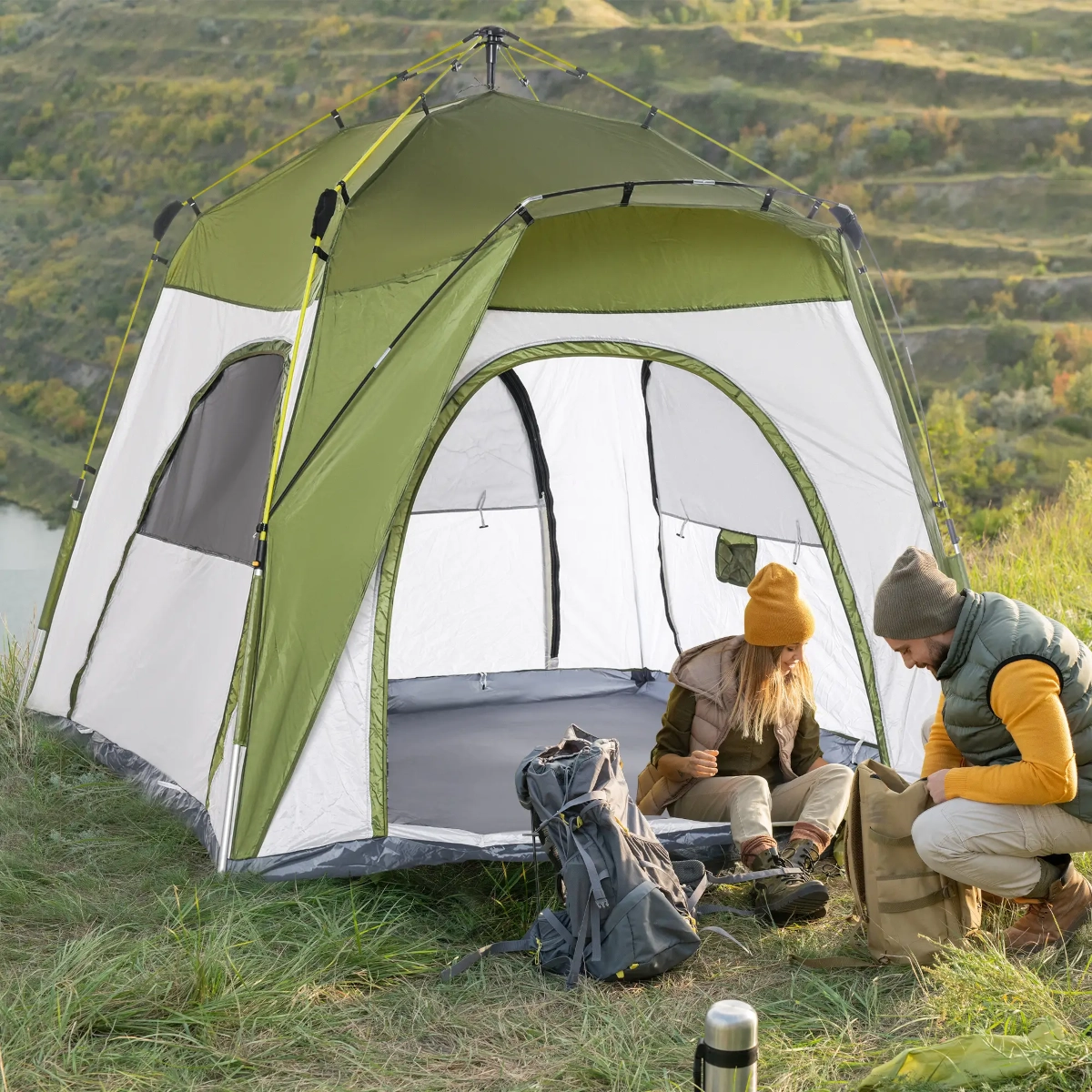 Classic dome-shaped tent pitched on grassy field under cloudy sky.