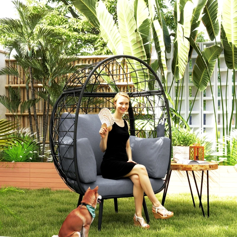 Stylish outdoor egg chair with a woman and dog in a garden setting.