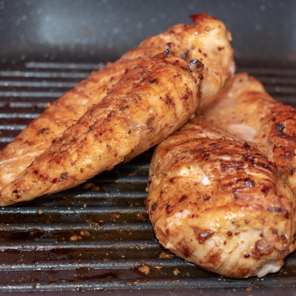 Grilled chicken on barbecue grill with char marks, cooked to perfection.