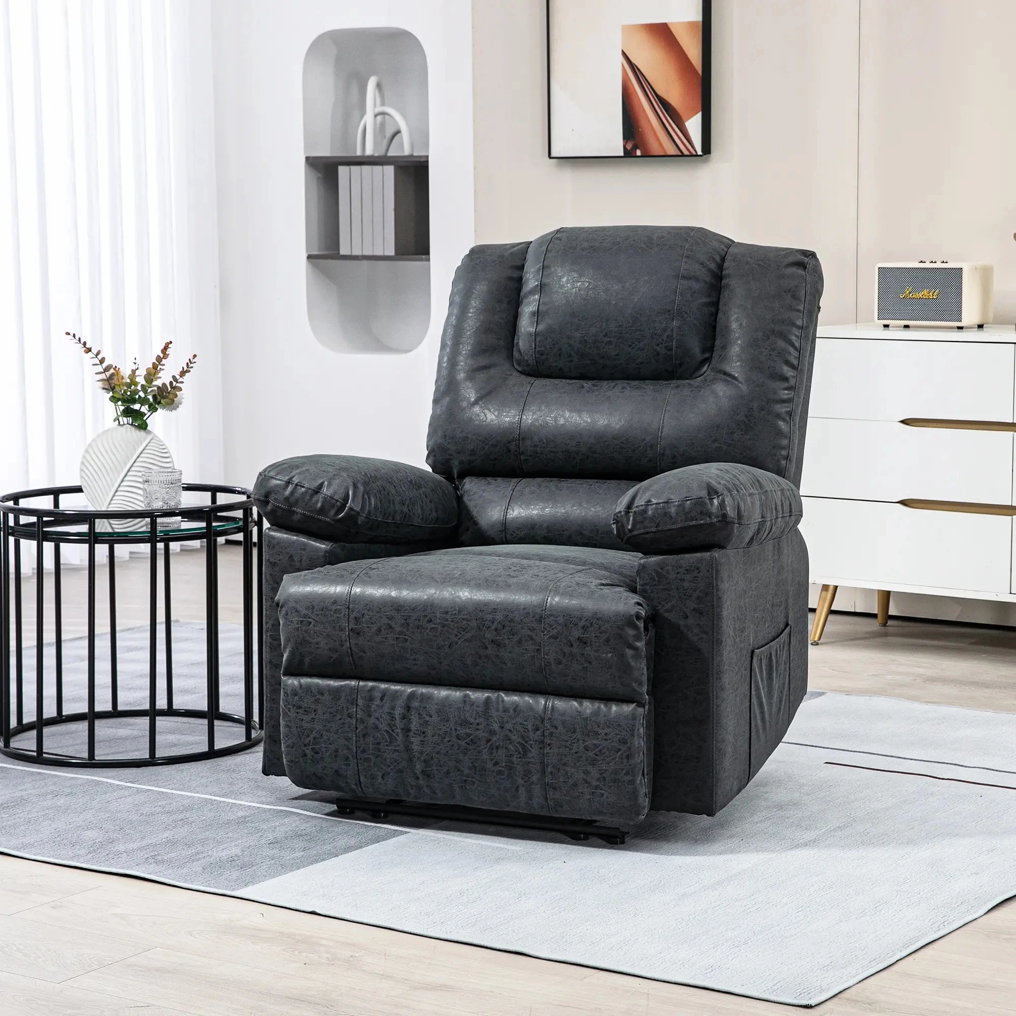 Plush black leather recliner chair in a bright room with a round black metal side table.