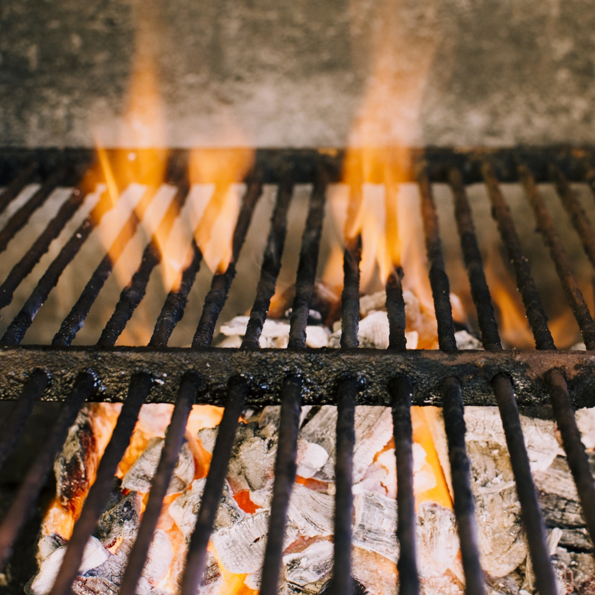 Outdoor grill being preheated with flames ready for chicken cooking.
