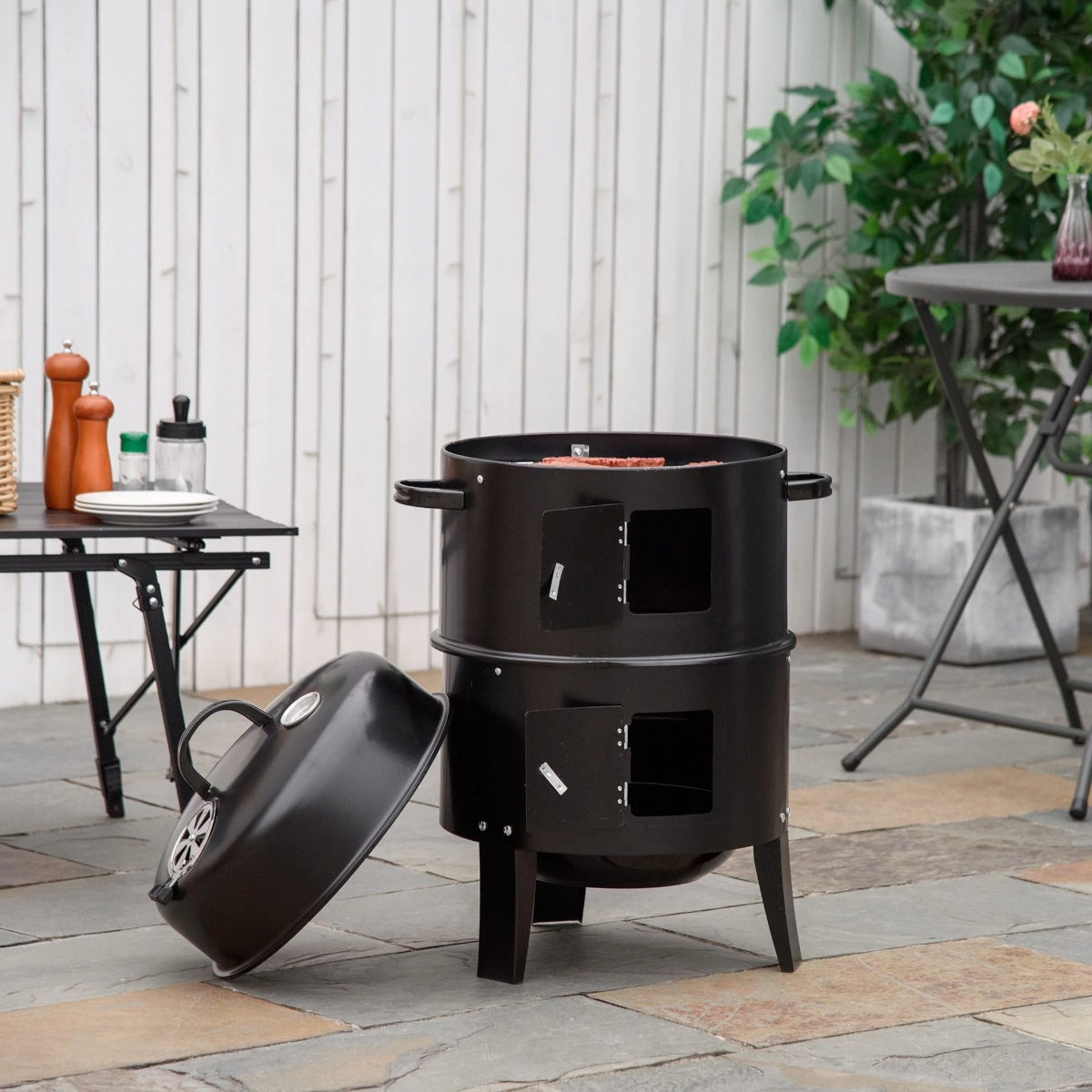 Vertical charcoal smoker grill with dual compartments and open lid, ideal for slow smoking meats.