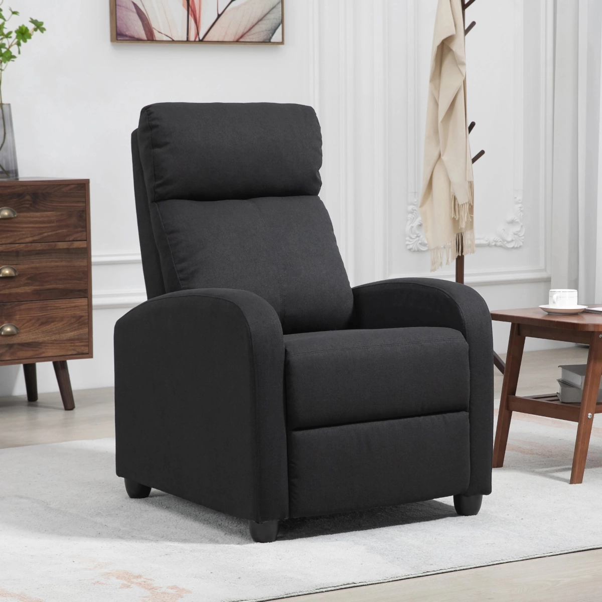 Black upholstered recliner in a bright room with white panel walls and modern wooden furniture.