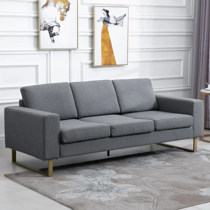 Modern gray sofa on a floral rug with framed artwork hanging above the backrest.