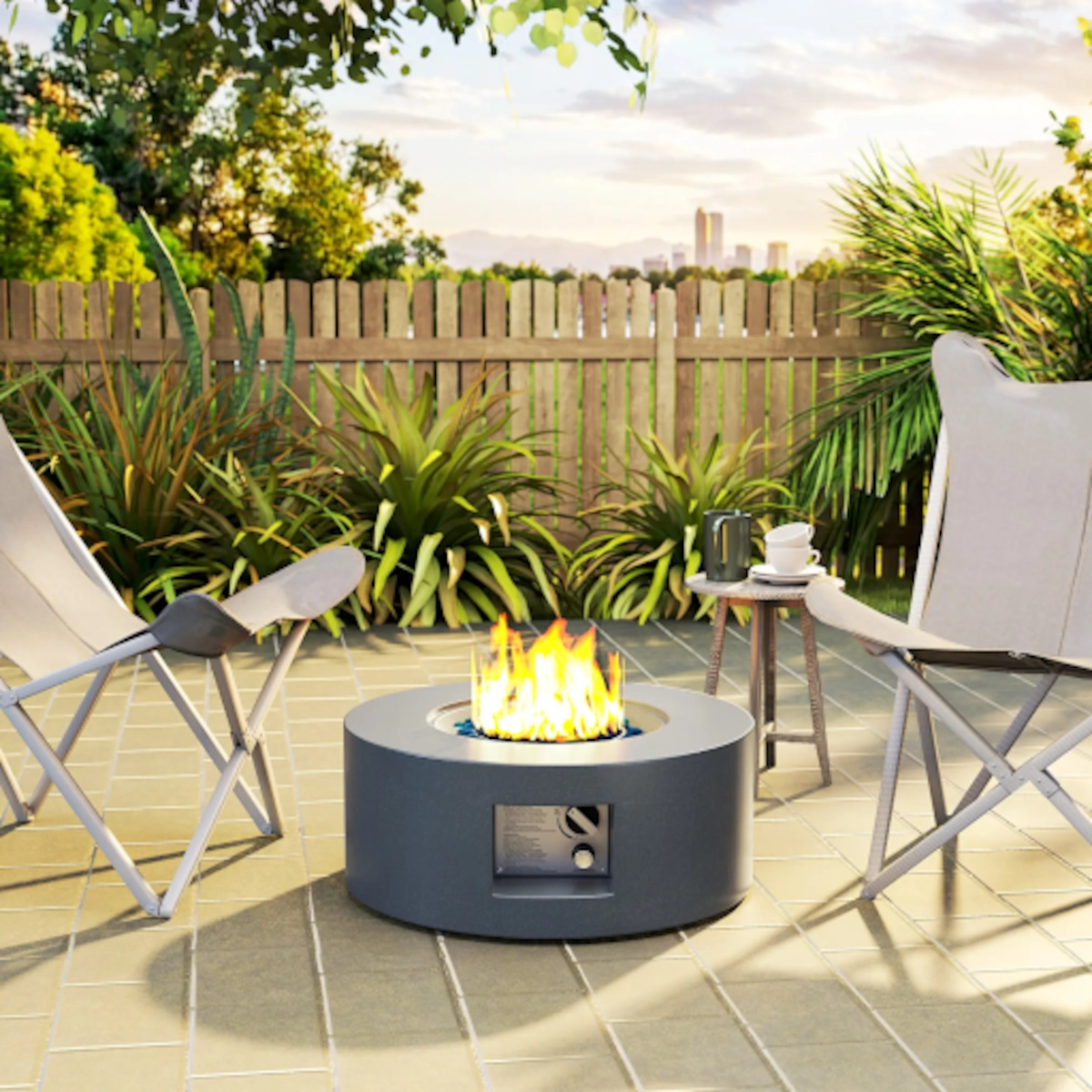 Modern propane fire pit lit on patio with chairs, table, and green backyard view.