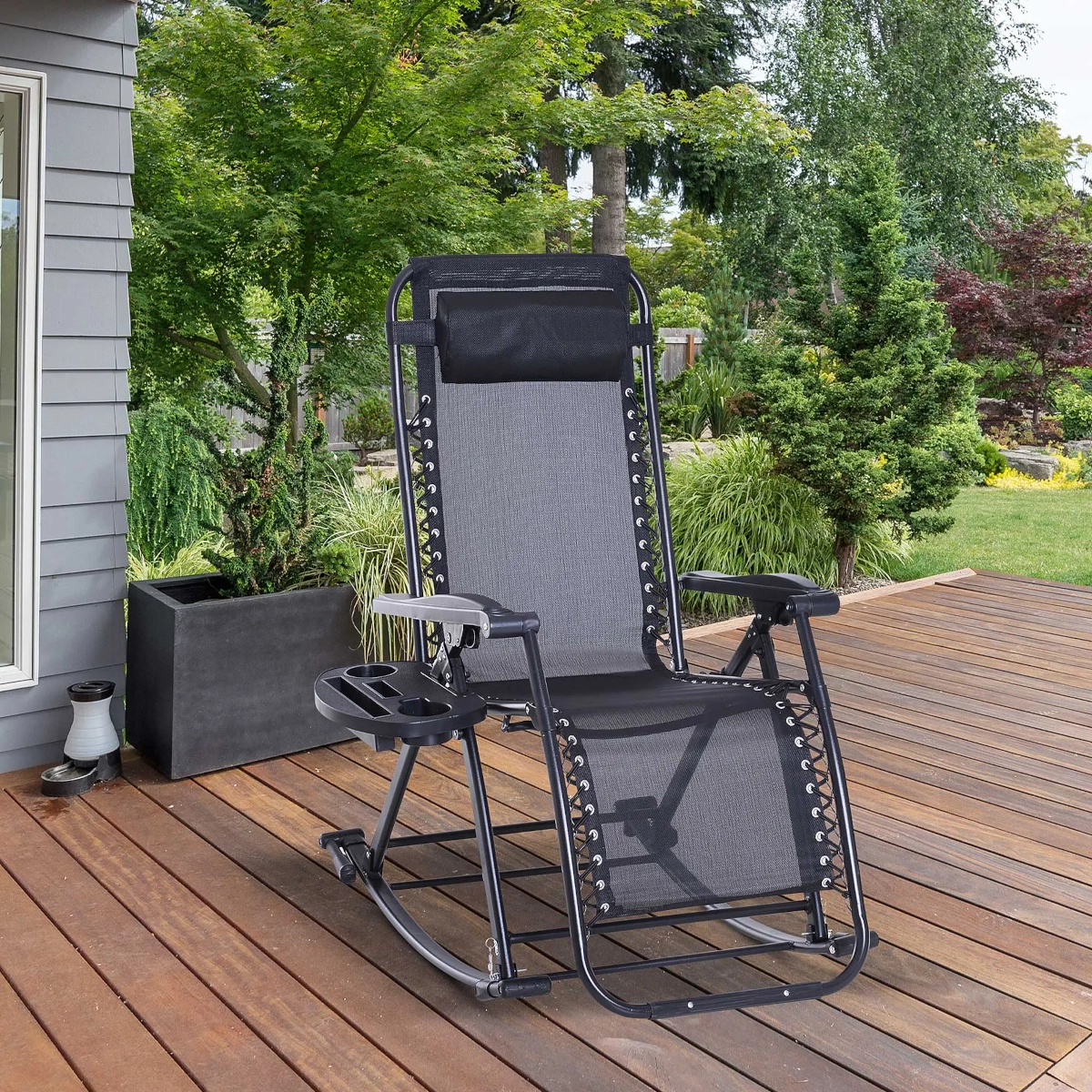Ergonomic zero gravity chair on a wooden deck, surrounded by lush green garden.