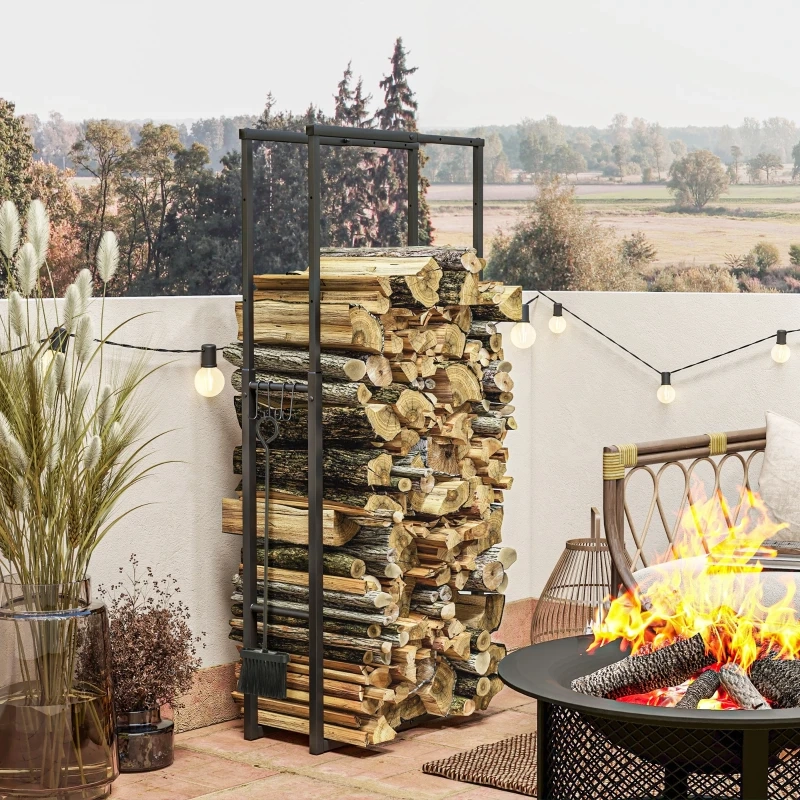 Outdoor adjustable firewood rack holding birch logs on a stone patio next to a white fence.