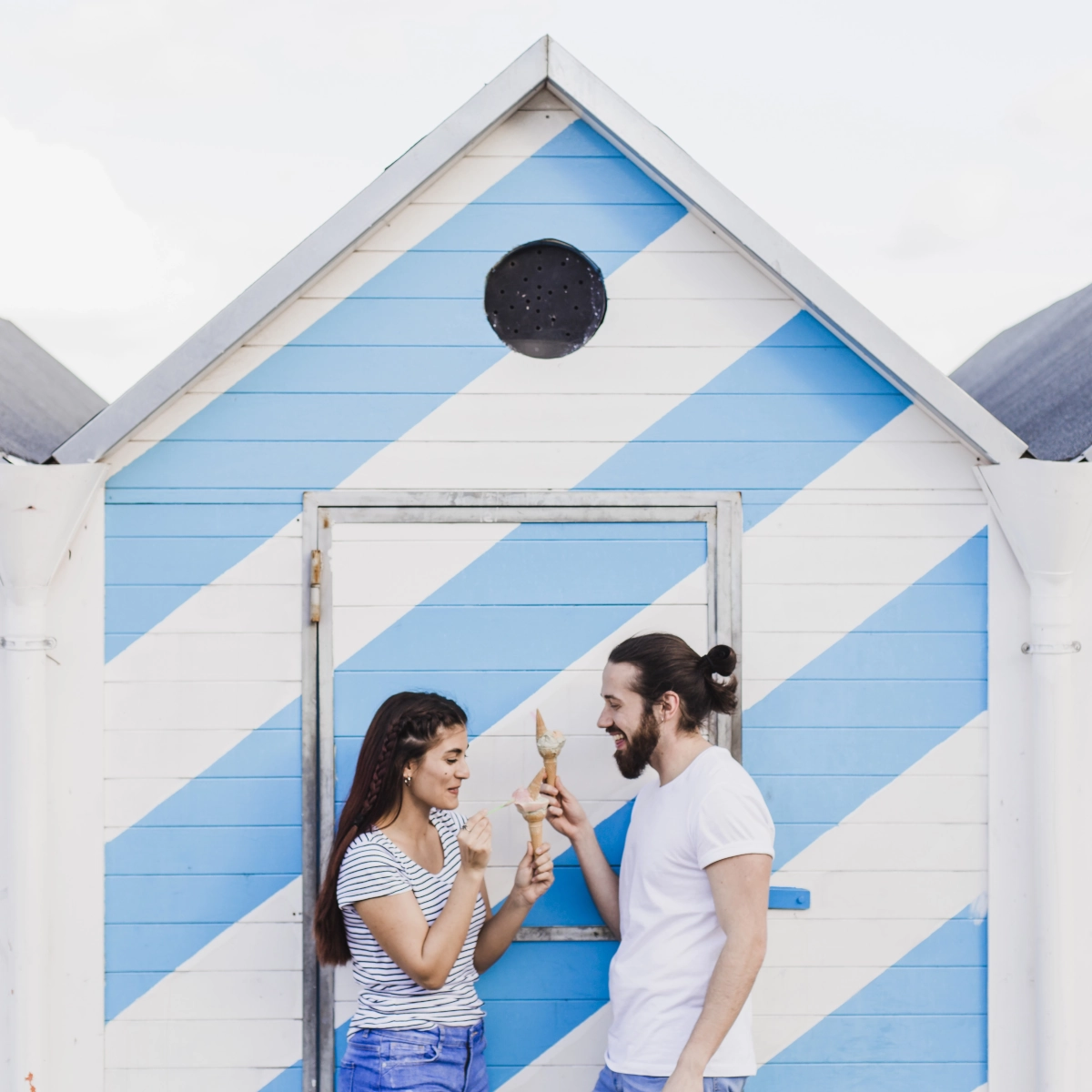 Hand holding color swatches against outdoor shed wall for paint color comparison.