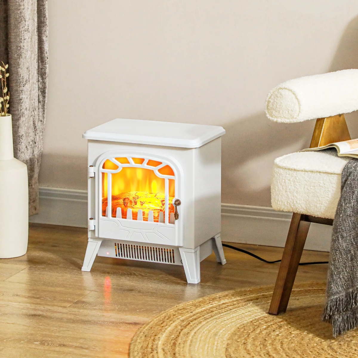 Compact white freestanding electric fireplace next to a cozy chair in a small reading corner.