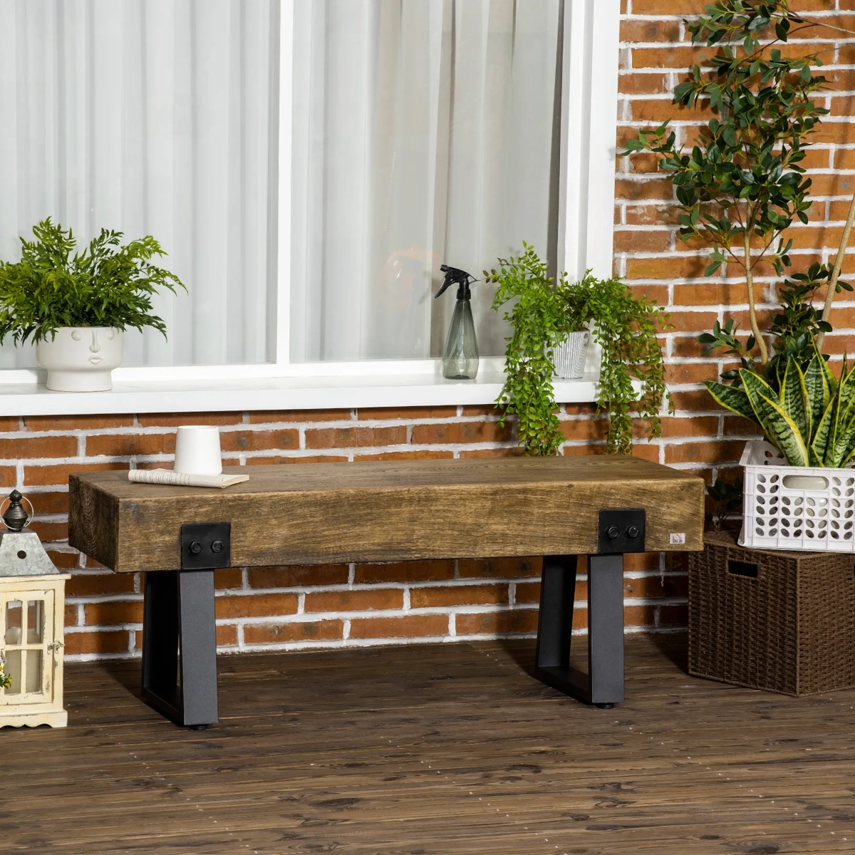 Modern rustic bench with wooden top and black metal legs placed against a brick wall.