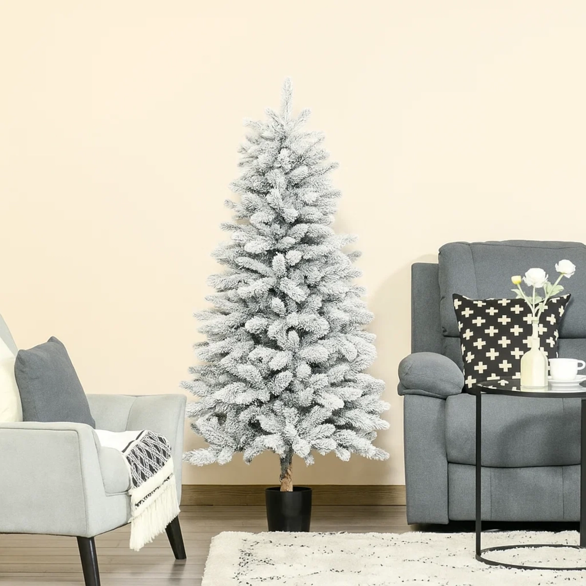 Artificial eucalyptus tree in black pot beside rattan nightstand and sofa.