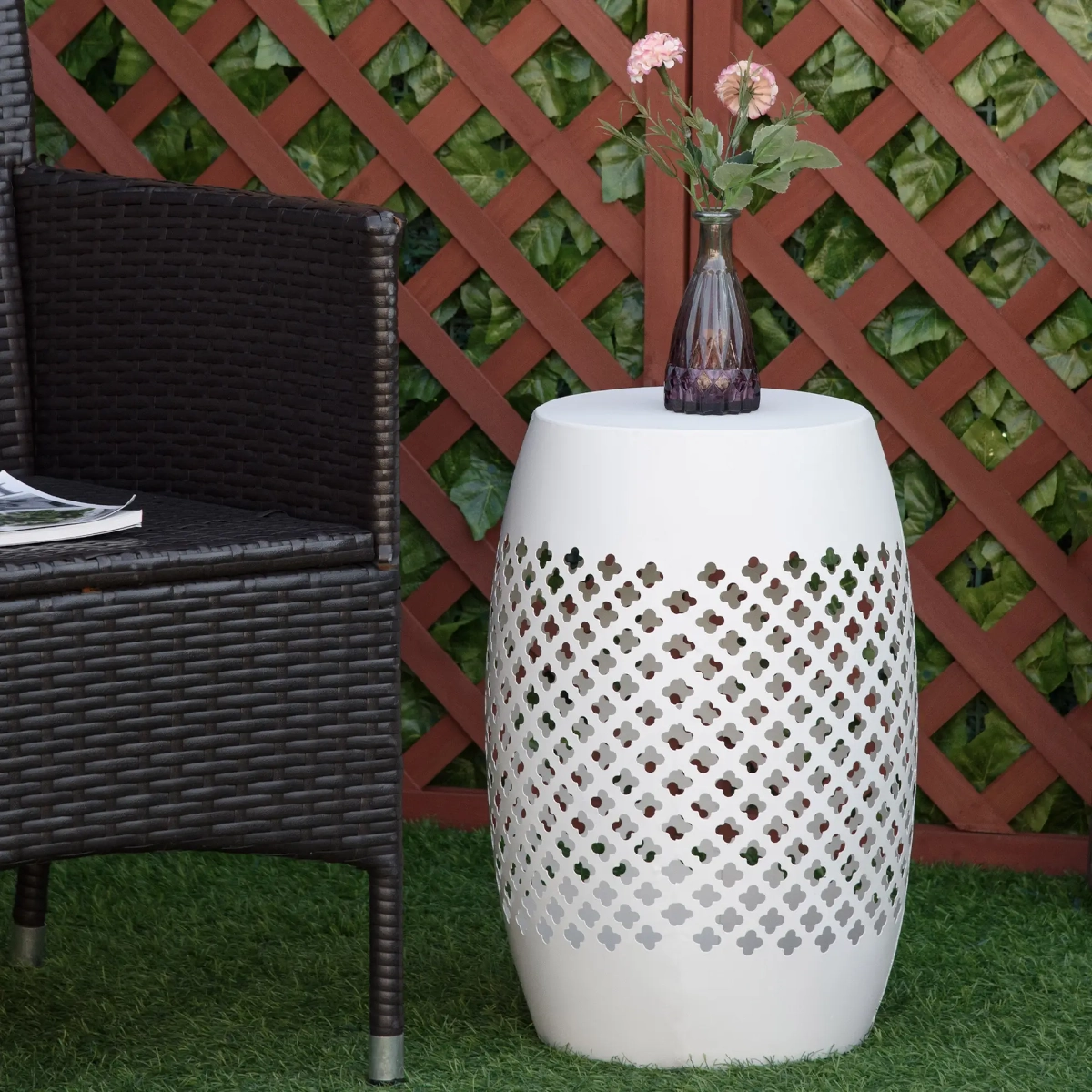Minimalist white hollow drum table with decorative perforations in an outdoor space.