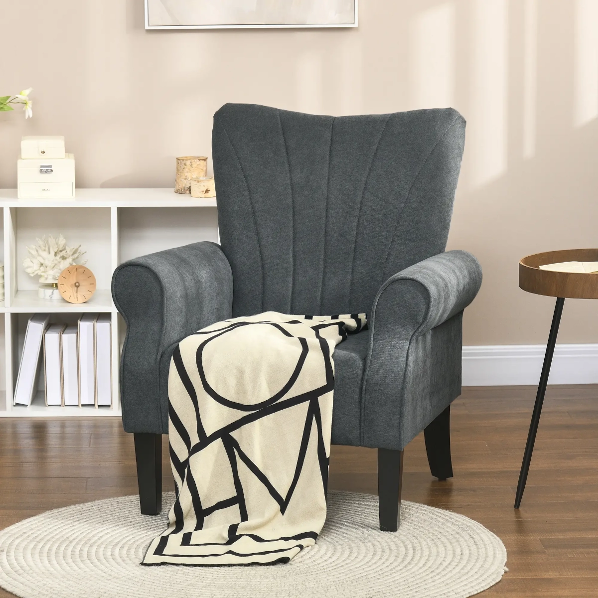 Dark grey accent chair with rolled arms and bold-patterned throw in a cozy neutral-toned room.