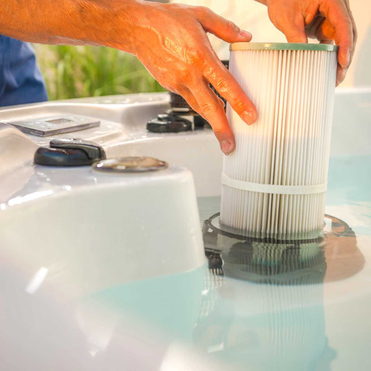 Hands replacing water filter cartridge in cold plunge tub for clean water circulation.