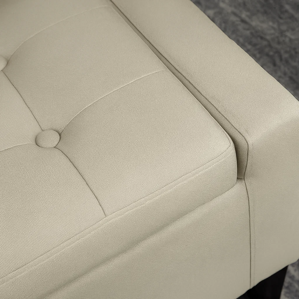 Close-up of beige upholstered ottoman showing neat tufted stitching and corner detail.