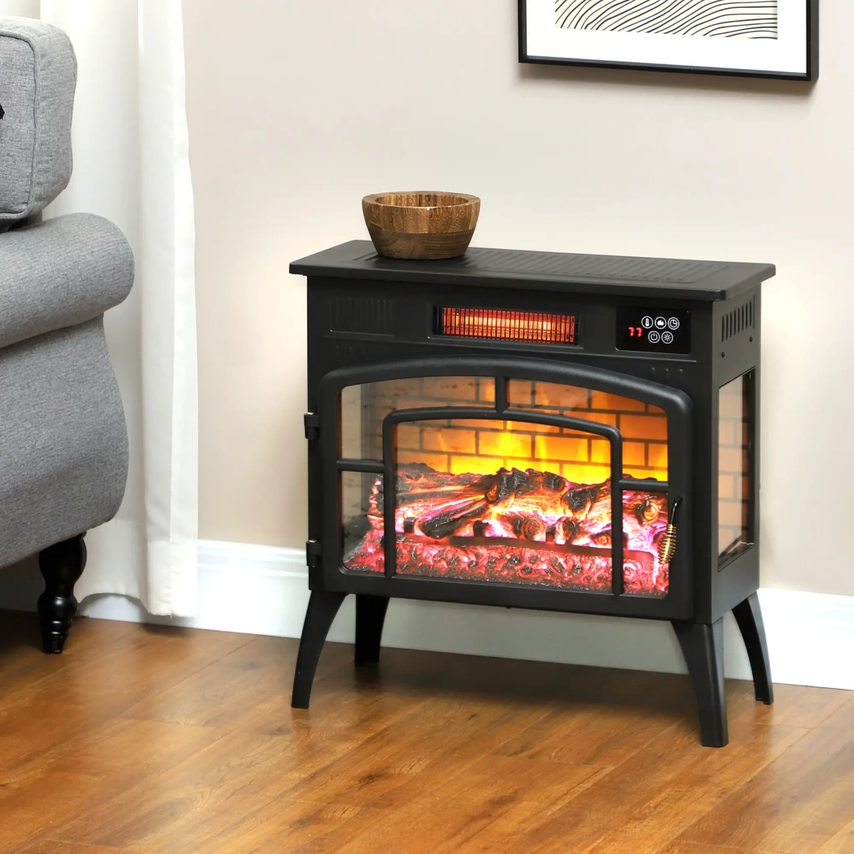 Infrared freestanding electric fireplace with glowing logs and brick interior beside a gray sofa.