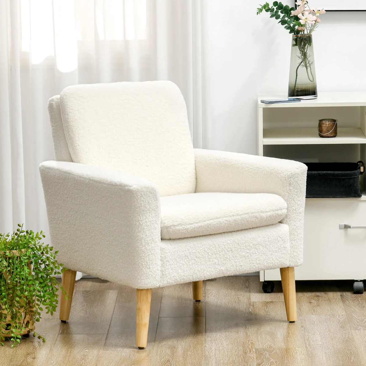 Cream boucle accent chair with light wood legs in a soft-lit corner with indoor plants.
