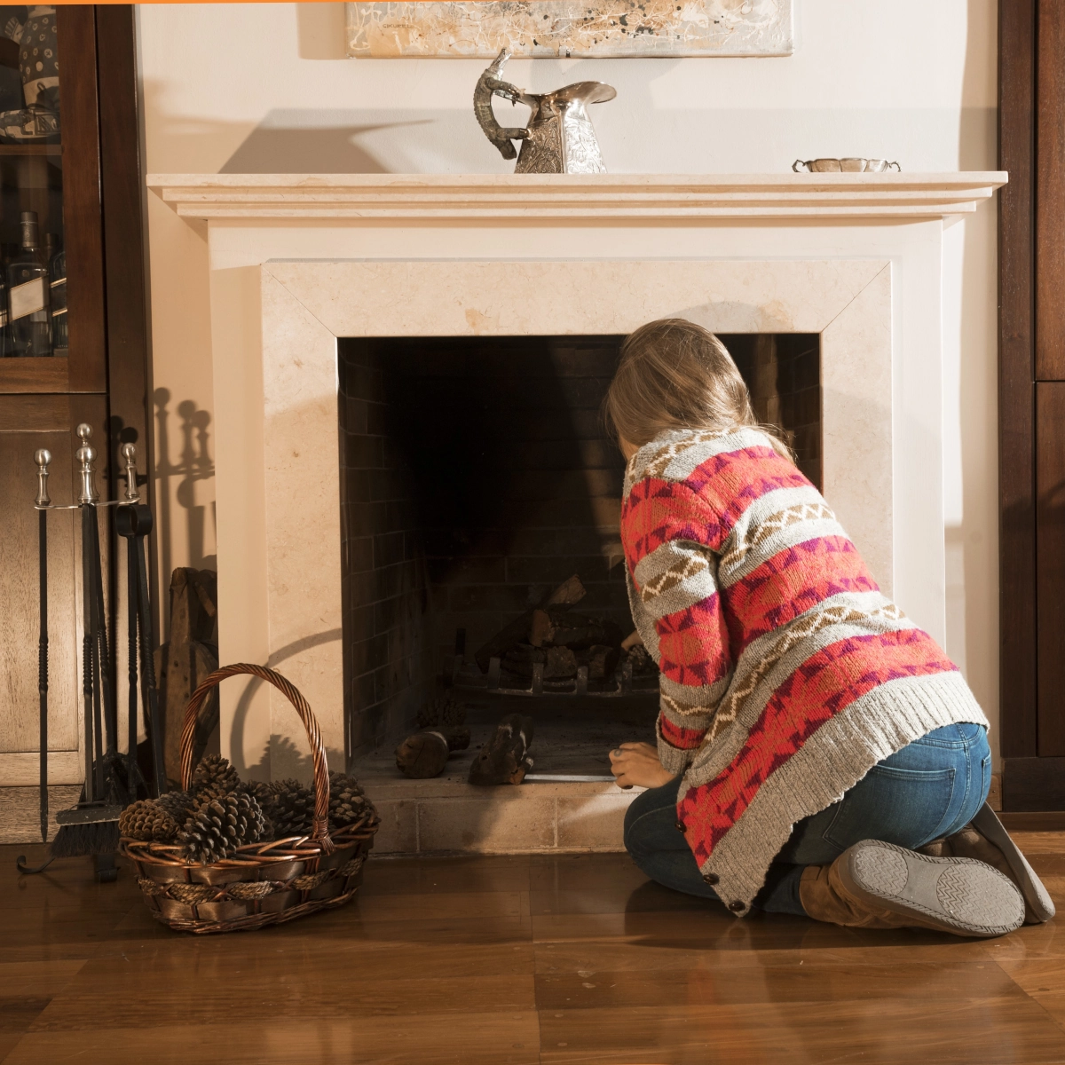 Woman in sweater tending a traditional wood fireplace with rustic basket