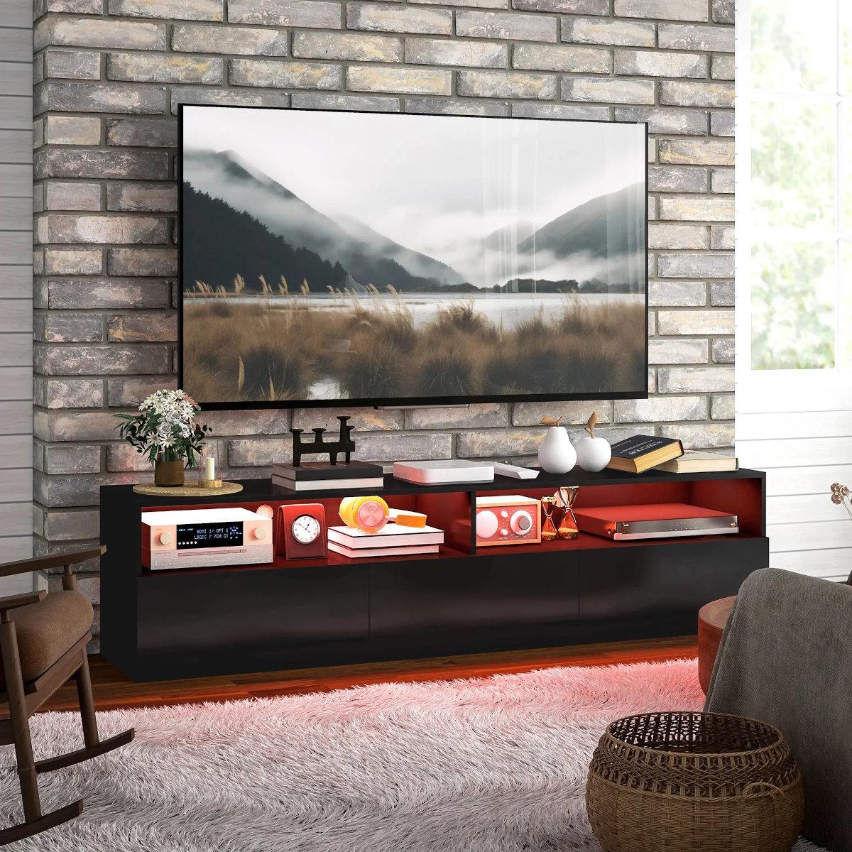 Brick wall-mounted TV above a black TV stand with red shelving and styled home accessories.
