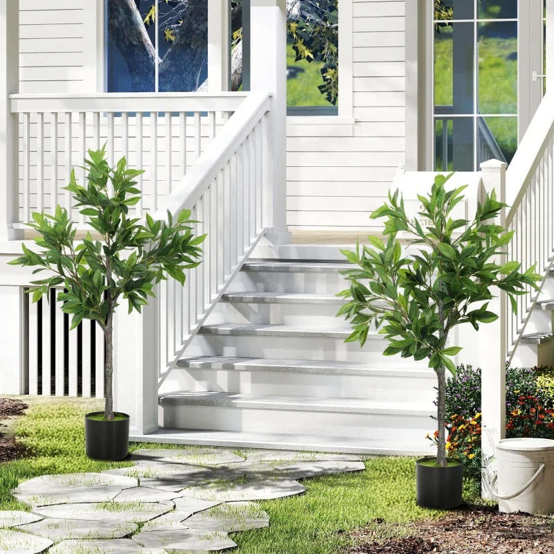Two artificial trees in black pots displayed on a front yard walkway by white steps.