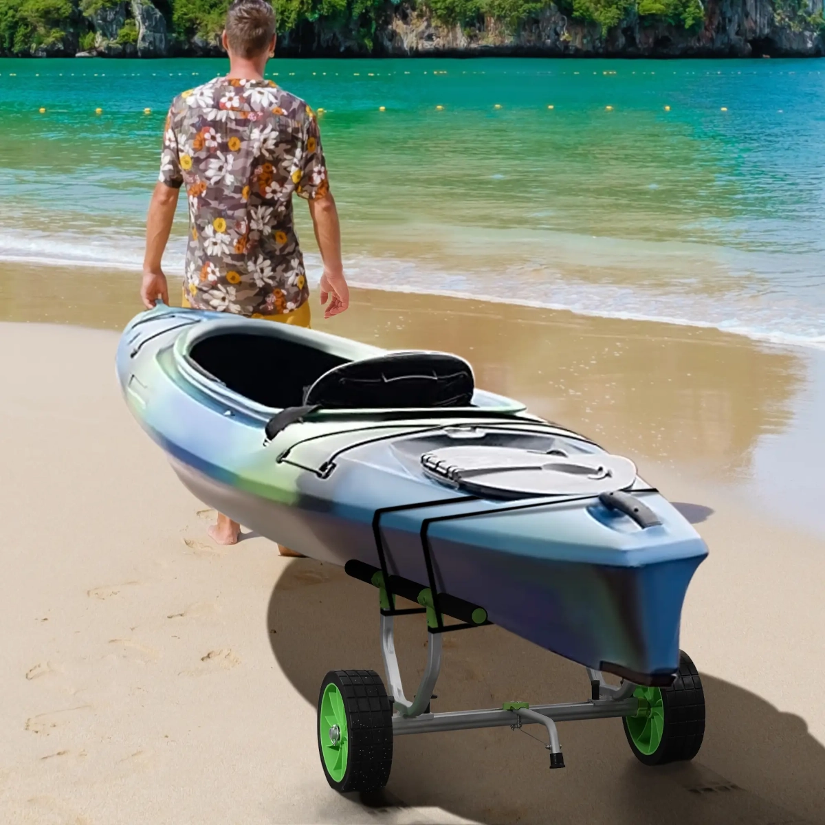 Kayak secured on green-wheeled cart being pulled along beach by man in floral shirt.