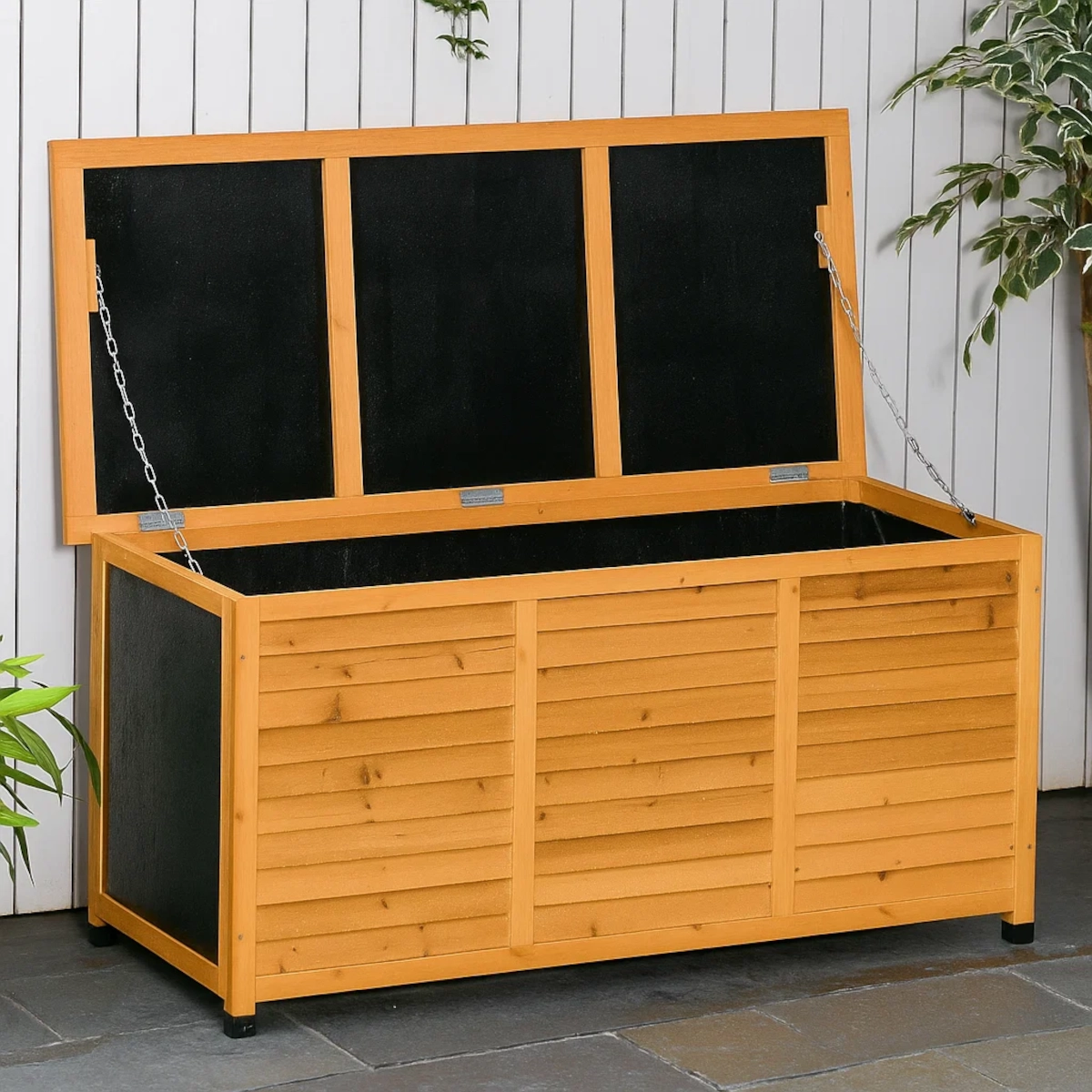Wooden storage box with open lid placed on blocks for outdoor waterproofing inspection.