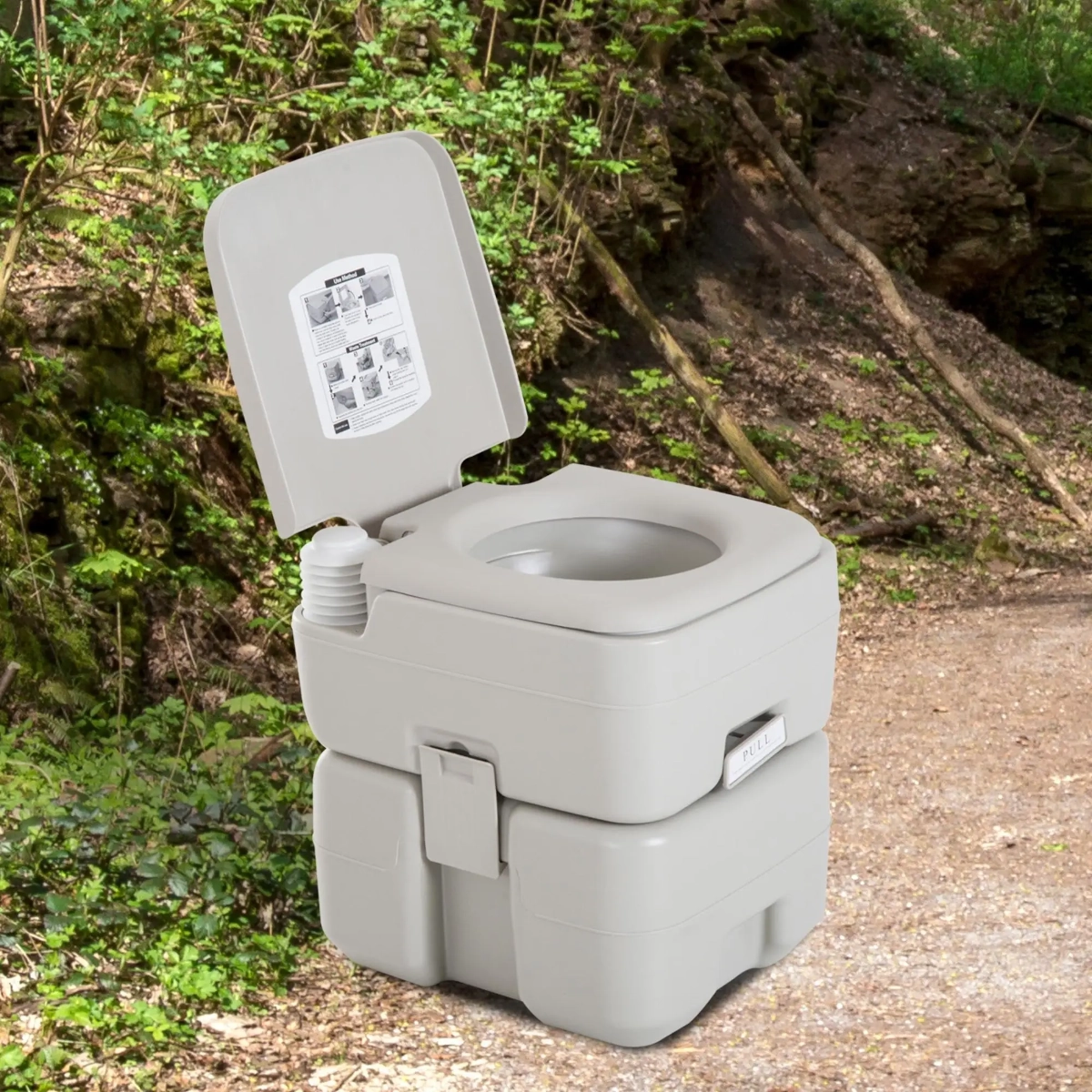 Portable travel toilet setup in a wooded camping area with trees.