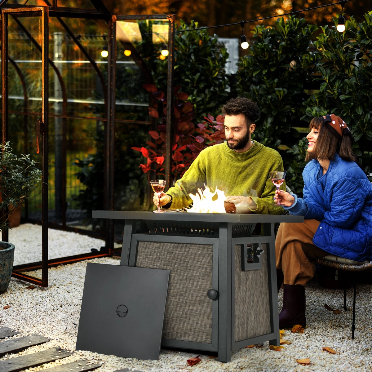 Couple enjoying drinks by a modern natural gas fire pit in a cozy backyard setting.