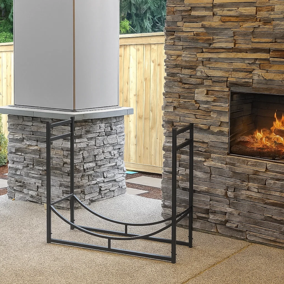 Metal firewood rack near outdoor fireplace with stacked stone background.