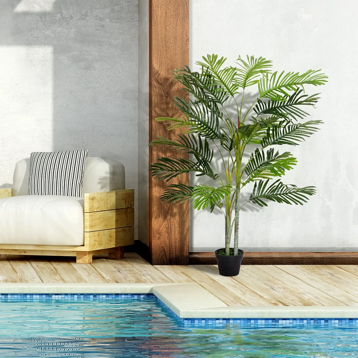 Artificial palm tree in black pot by poolside, next to modern wooden chair and light wall.