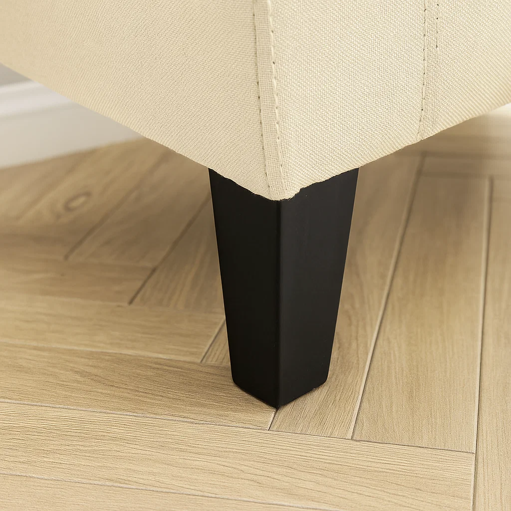 Close-up of ottoman leg securely attached to the upholstered base on wood floor.