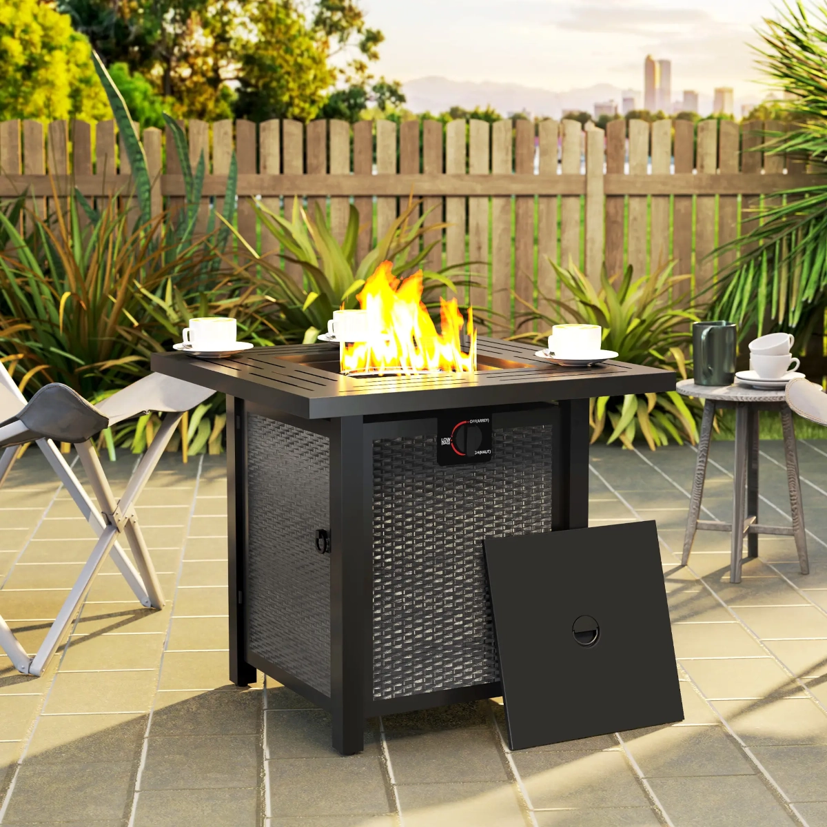 Black round smokeless fire pit on gravel patio beside outdoor lounge furniture and plants.