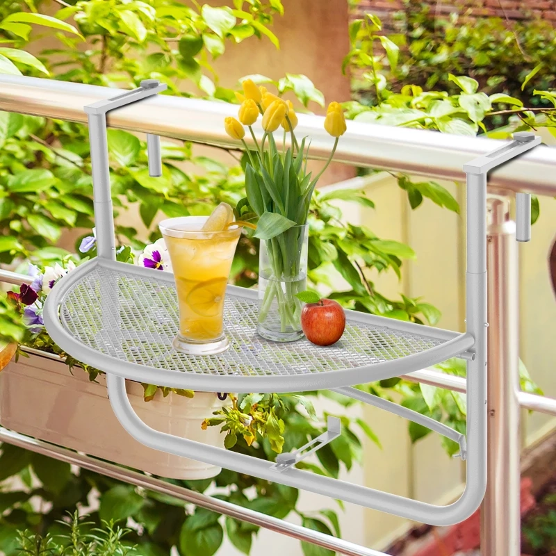 Half-round mesh balcony table with yellow tulips, lemonade, and apple among green garden plants.
