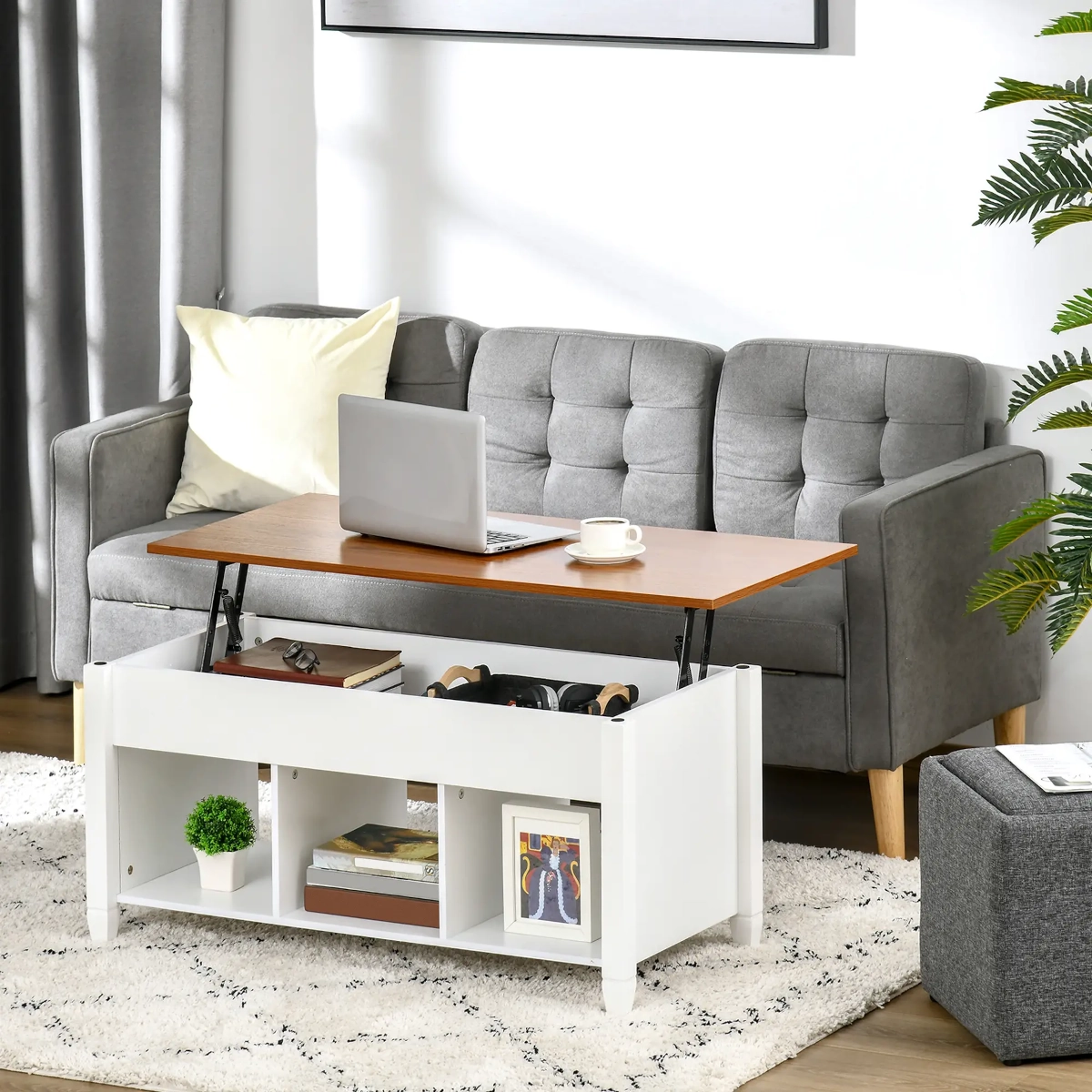 Lift-top coffee table open to reveal storage with books and plants, set in a bright lounge.