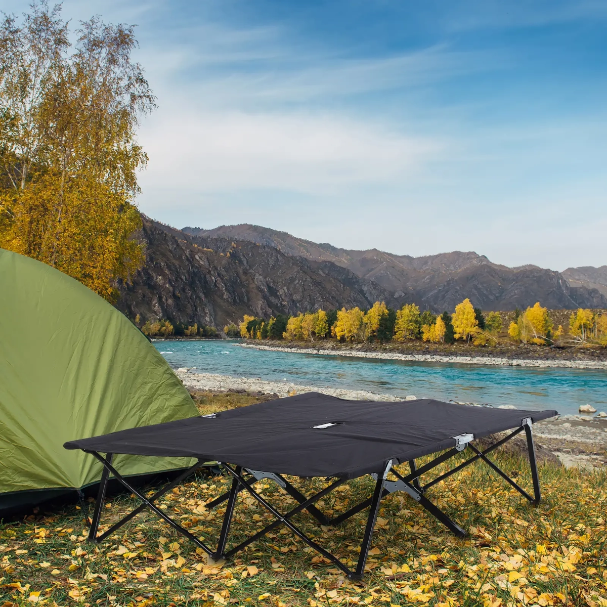 Large two-person cot with dual-frame support set up on flat surface near tent.
