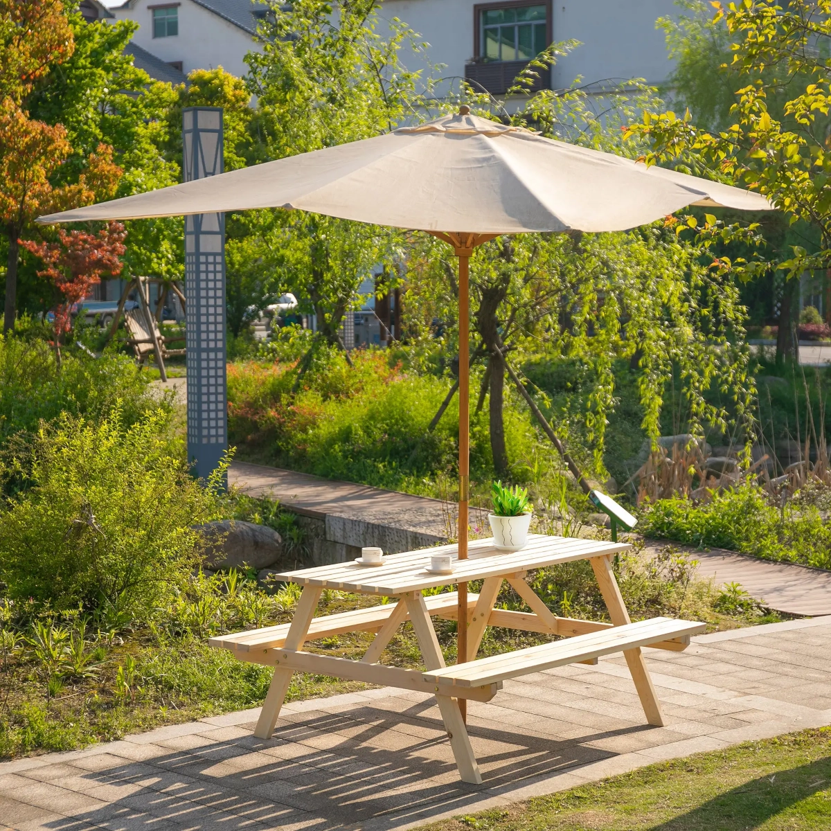 Picnic table with a large umbrella providing shade in a sunlit garden area.