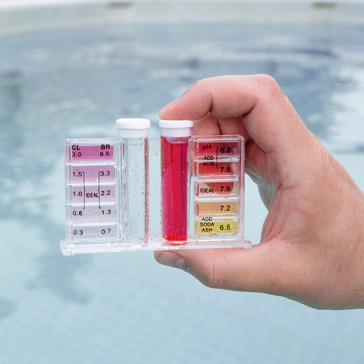 Hand holding pool water testing kit near cold plunge tub to monitor water quality.