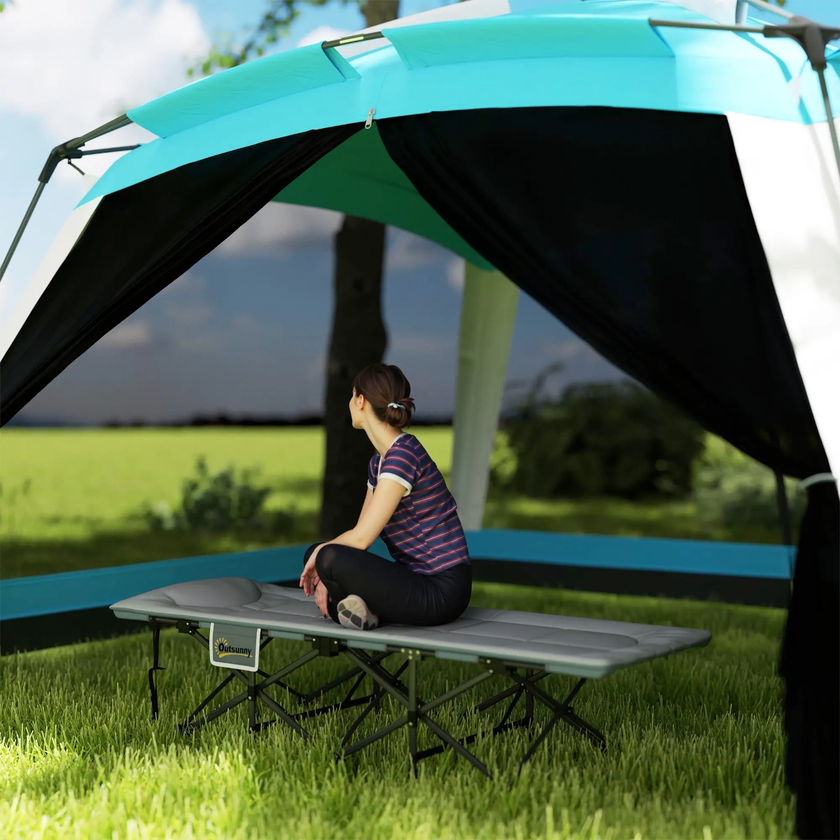 Extra-wide camping cot with padded cushion and gear storage pocket shown in forest clearing.