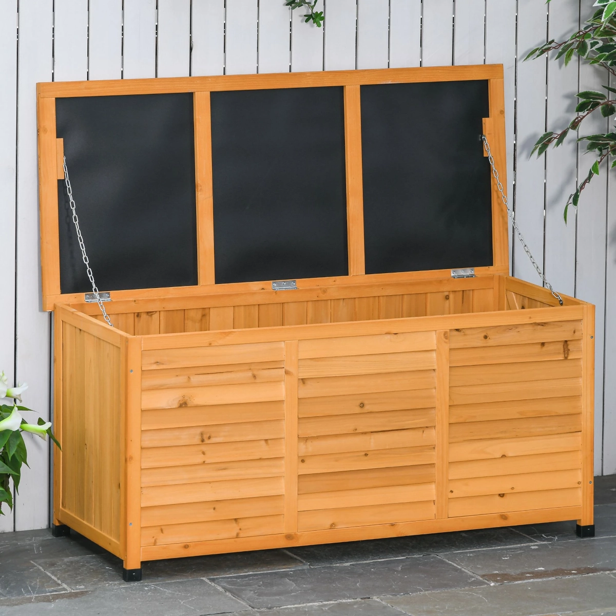 Rustic wooden storage chest placed on a porch with potted plants and a watering can nearby.