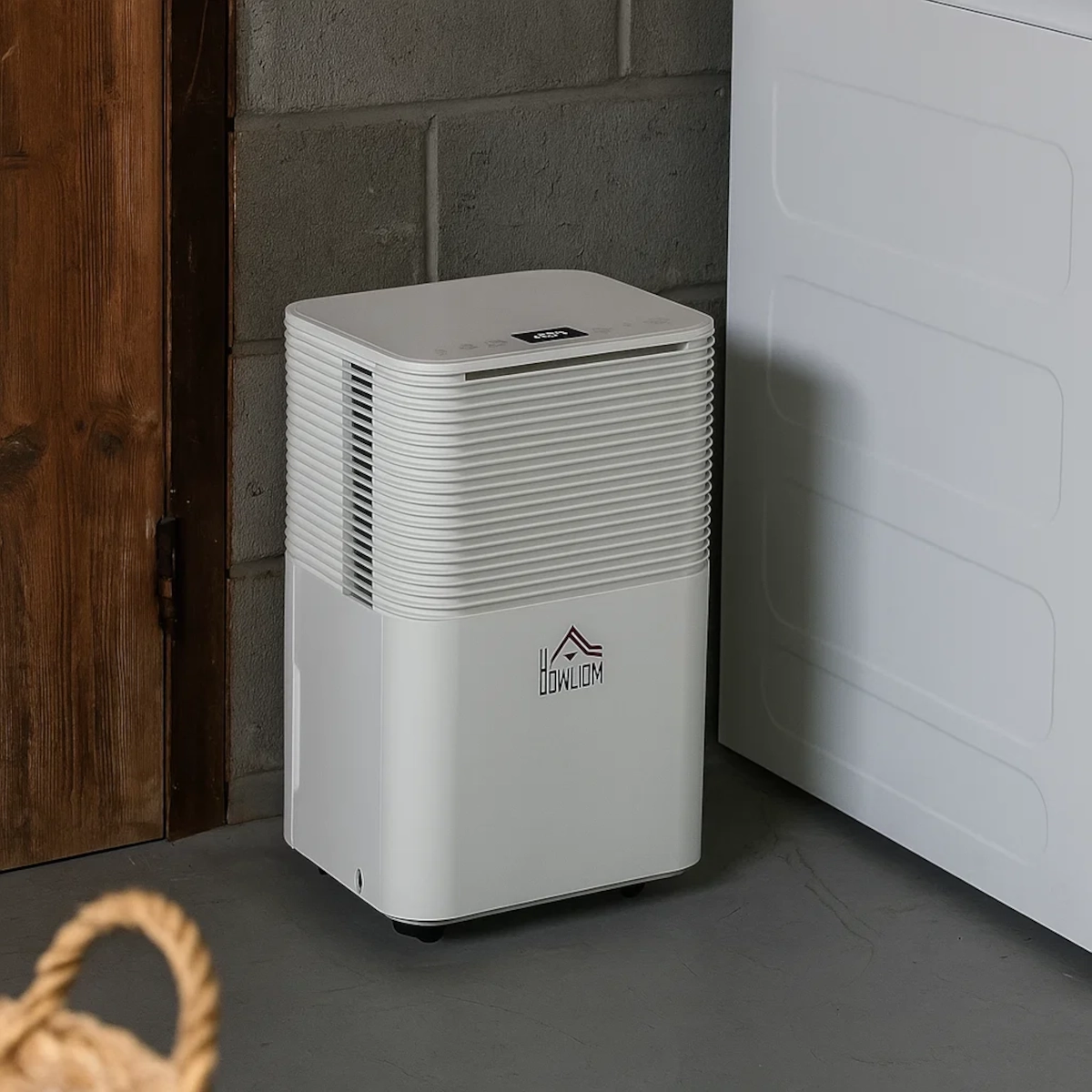 White HOMCOM dehumidifier placed beside washing machine in a basement laundry area.