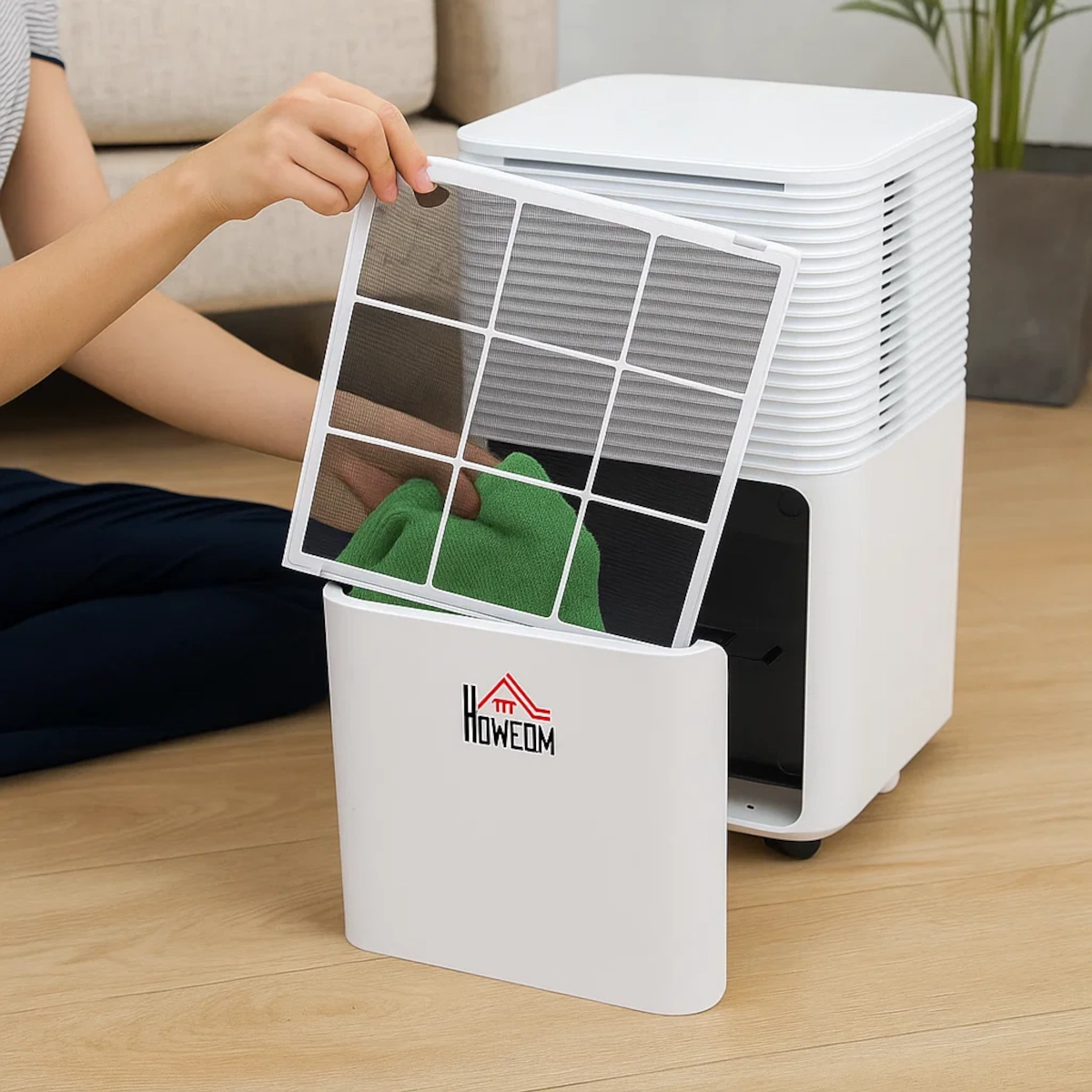 Person removing mesh filter from white HOMCOM dehumidifier for cleaning at home.
