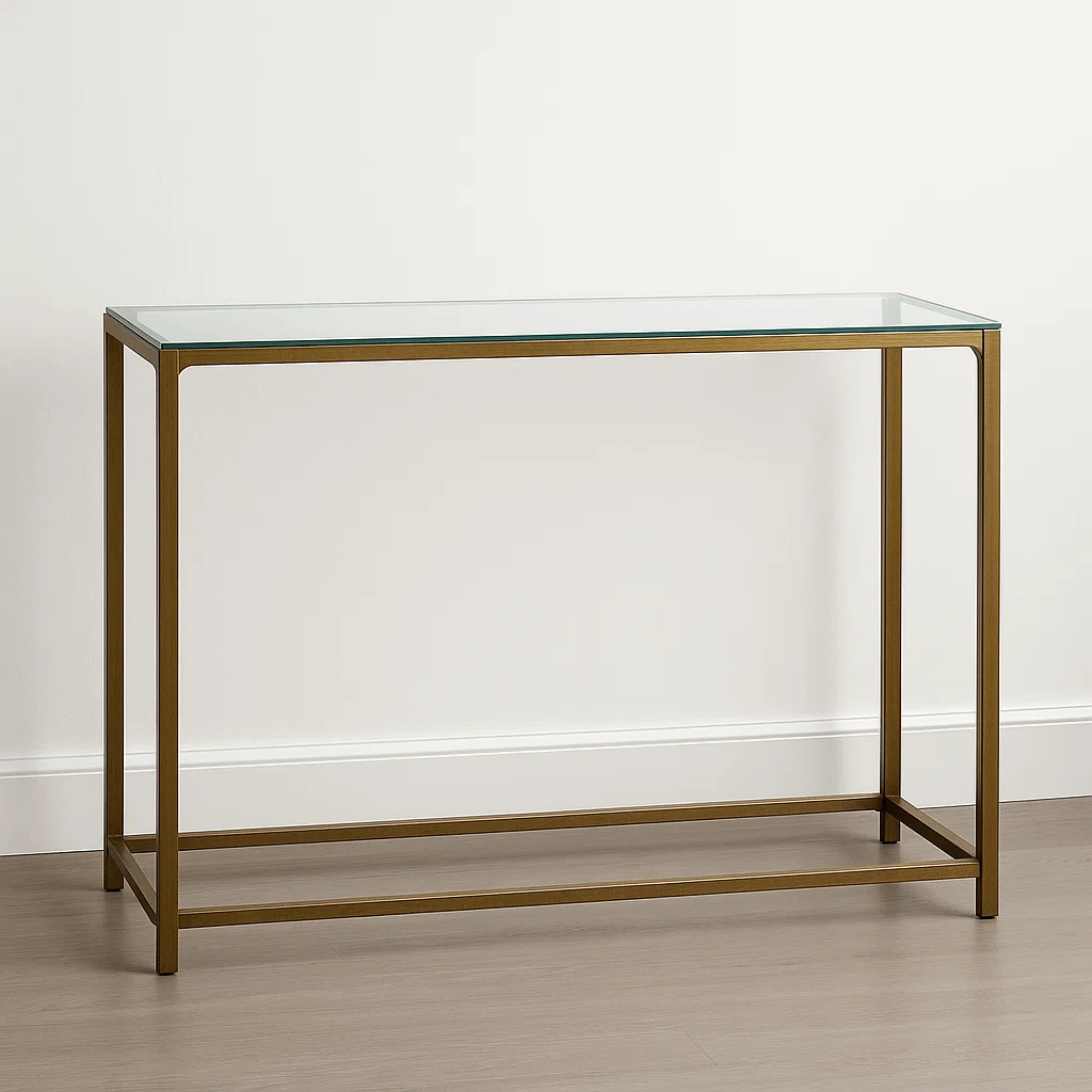 Minimalist glass-top console table with slim bronze metal frame against a light wall and wood floor.