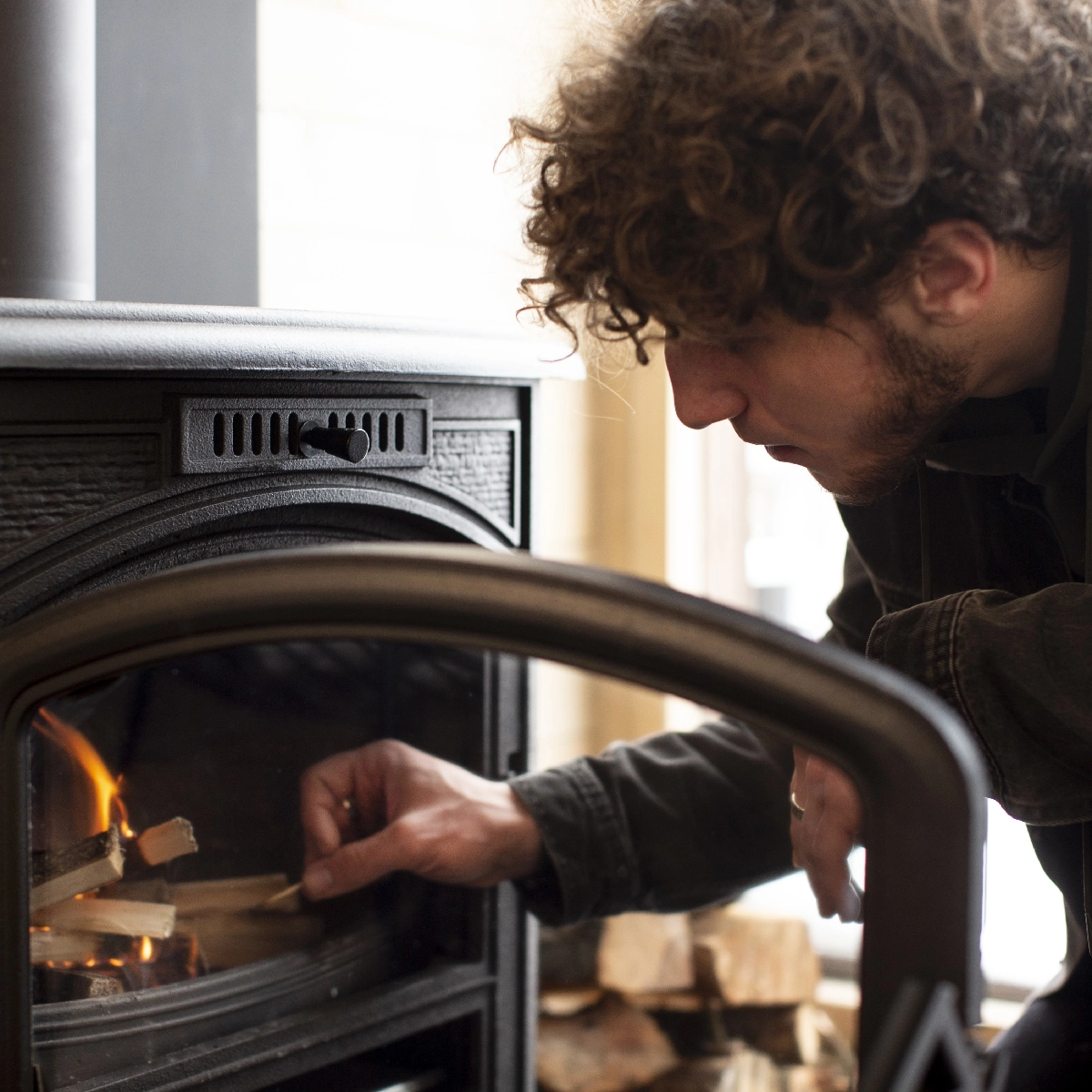 Person adjusting logs or inspecting the interior of an electric fireplace before use.