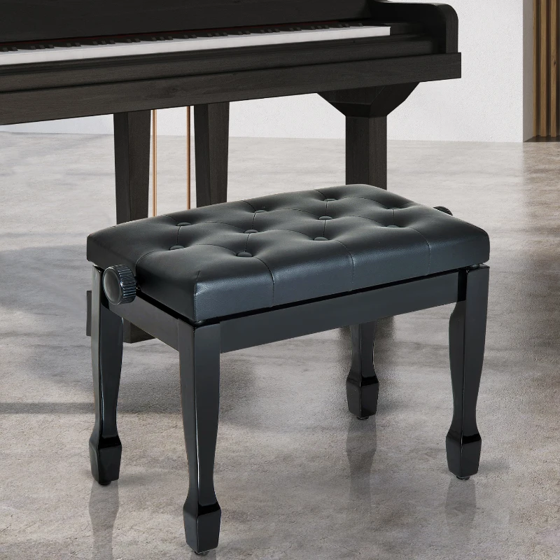 Black tufted piano bench placed in front of upright piano on polished concrete floor