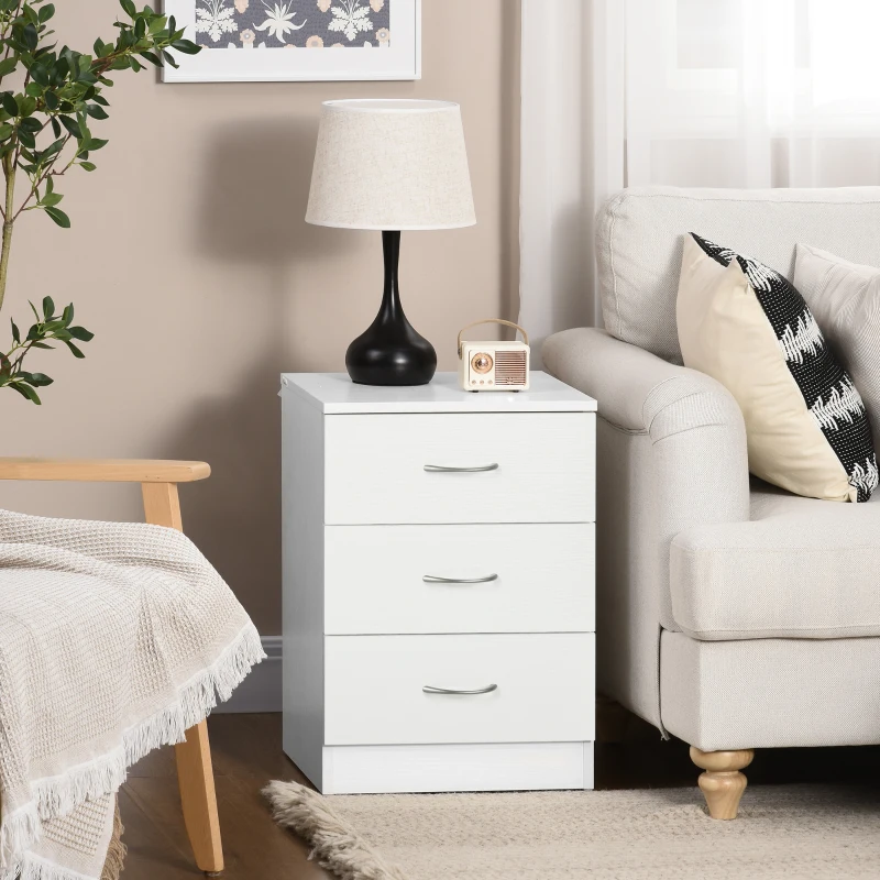White three-drawer bedside table beside sofa with lamp, mini radio, and cozy throw blanket.