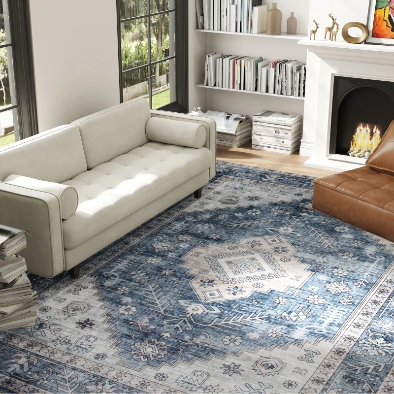 Blue patterned area rug placed under sofas in a bright living room with bookshelf and fireplace decor.