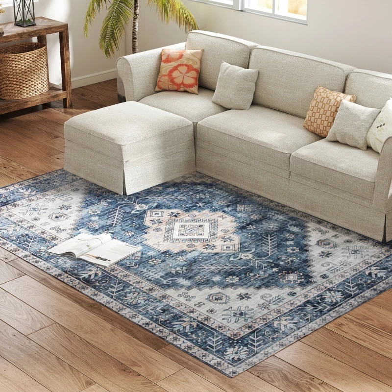 Blue patterned rug placed beneath light grey sectional in coastal-themed living room with wood floors.