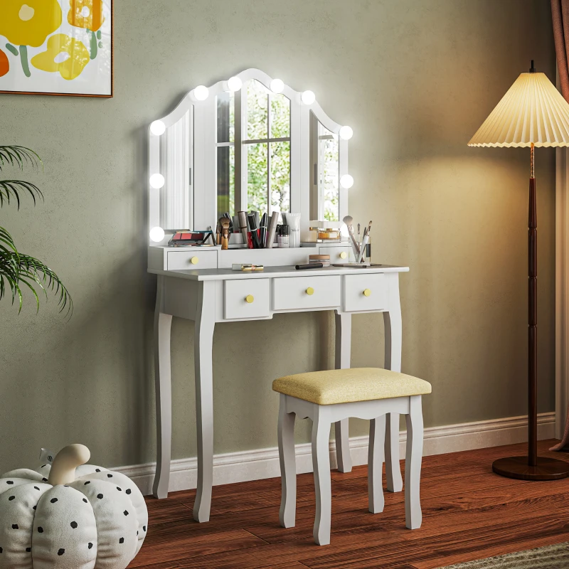White vanity table with Hollywood-style mirror lights, matching stool, and makeup setup in a cozy room.