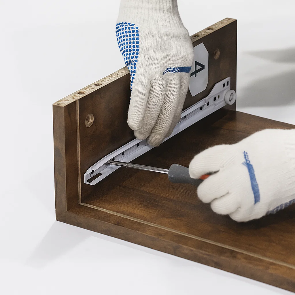 Man kneeling while attaching metal cross rails to console frame.